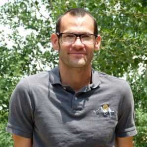 Outdoor portrait of team member wearing glasses and branded polo, part of the electrical team in Colorado Springs.