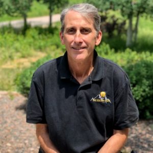 Team member seated outdoors in branded polo, photographed for the electrical team collection in Colorado Springs.