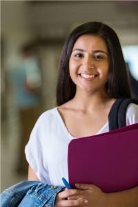 Student holding folder in a hallway, reflecting opportunities for administrative internship program in Colorado Springs.